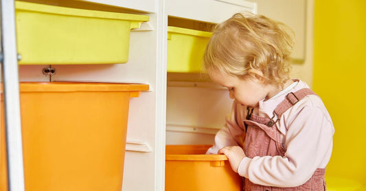 Aufräumen mit Kindern: Ein Kind sortiert Bauklötze in eine Kiste.